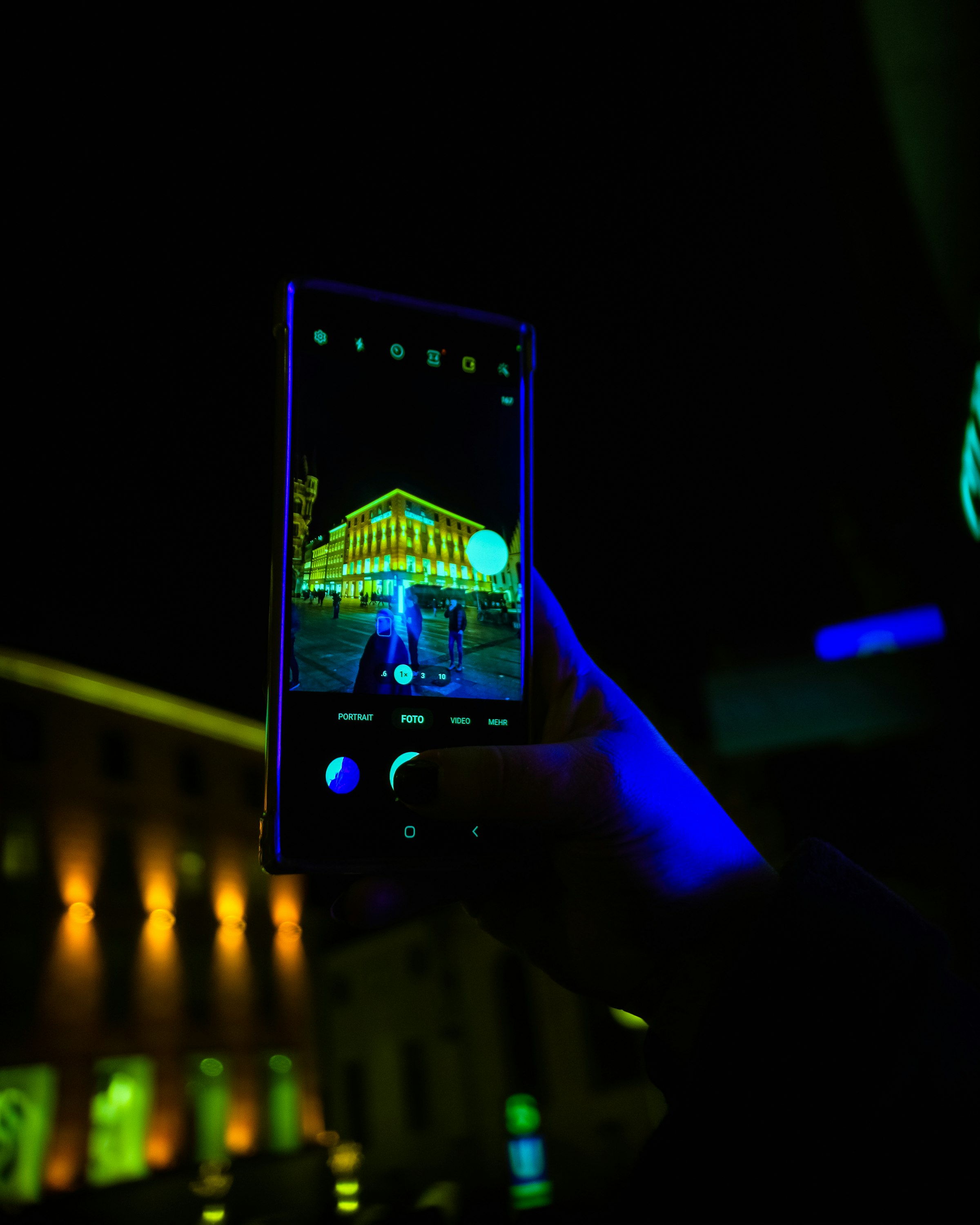 Hand holding a phone at night with neon lights in the background